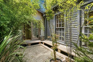 Un jardín japonés tradicional con terraza de madera, farol de piedra y plantas de bambú.