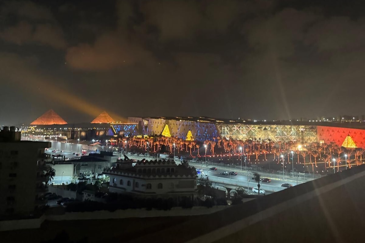 A nighttime view of a cityscape with illuminated buildings and a prominent pyramid structure.