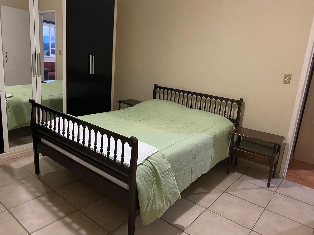 Um quarto com uma cama, mesa de cabeceira e guarda-roupa.