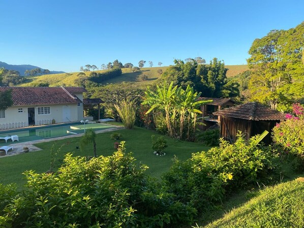 A residential property with a swimming pool, a small garden, and a hill in the background.