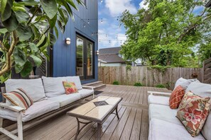 An outdoor patio with a blue building, wooden deck, and string lights. - Southern Souls 715-Downtown Nearby-Sleeps 6 (Nashville)