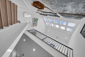 Un interior moderno con una escalera, tragaluces y un cuadro en la pared.