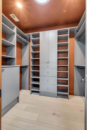A walk-in closet with multiple shelves and drawers, a ceiling light, and a wooden floor. - Southern Souls 715-Downtown Nearby-Sleeps 6 (Nashville)