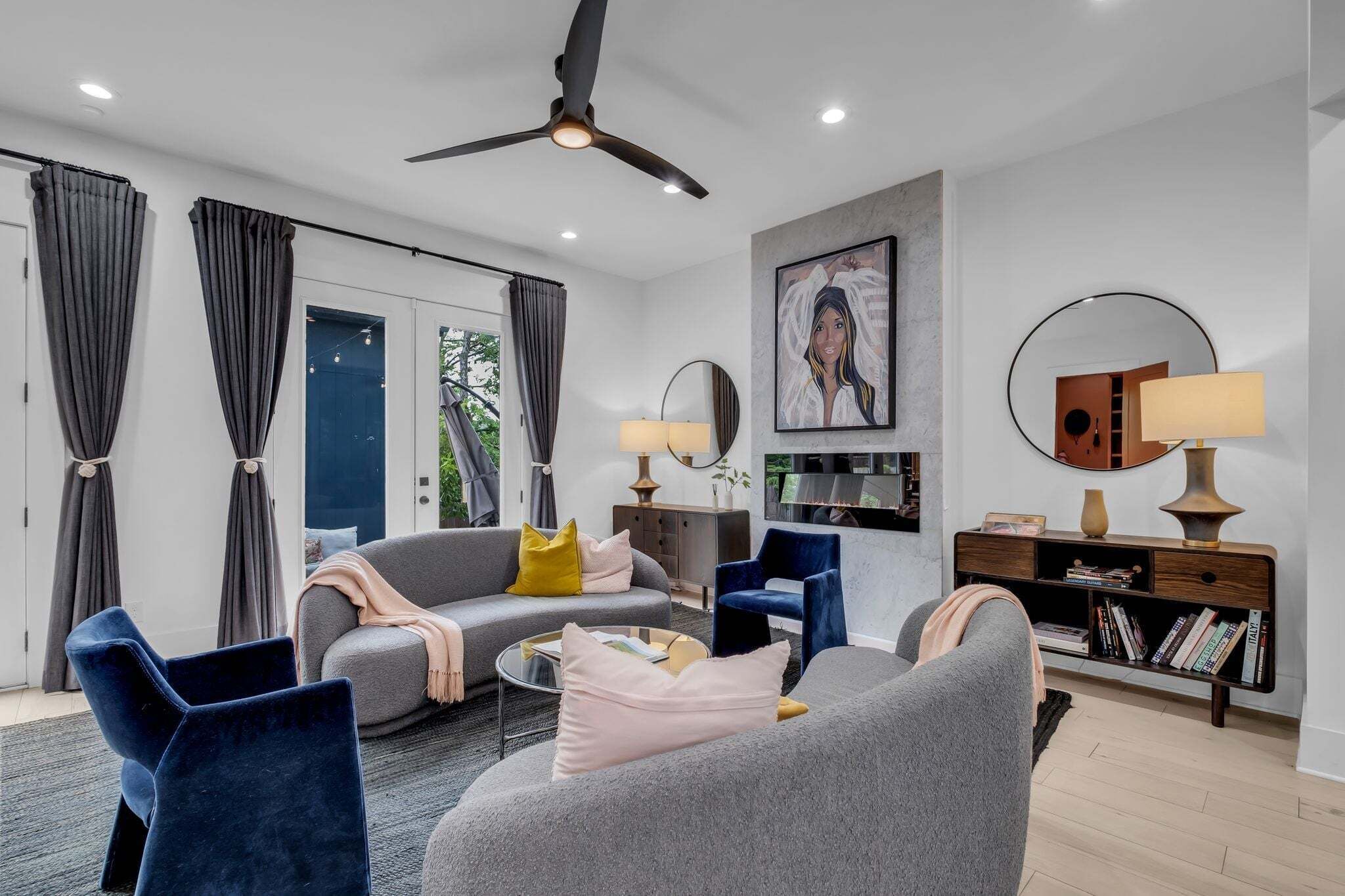 A modern living room with a grey sofa, blue armchairs, a coffee table, and a bookshelf.