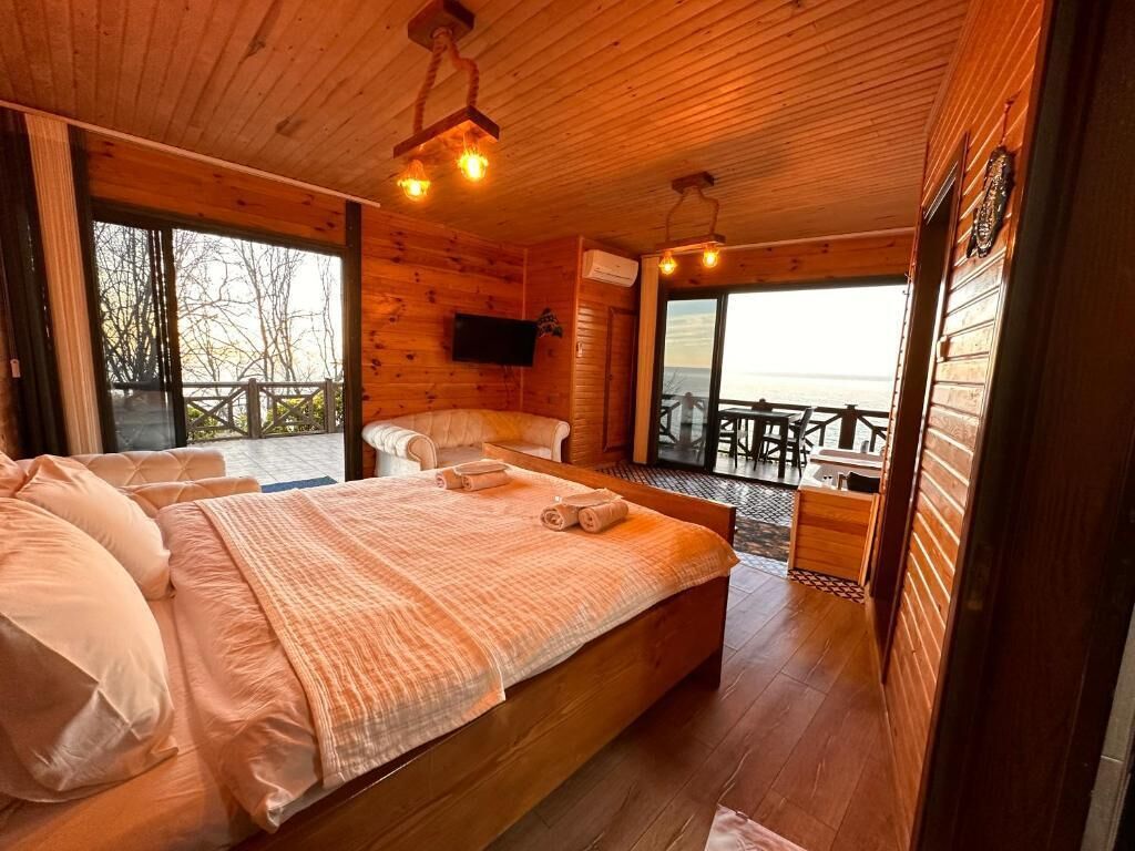 Una baita in legno con un letto grande, una televisione a muro e un balcone con vista.