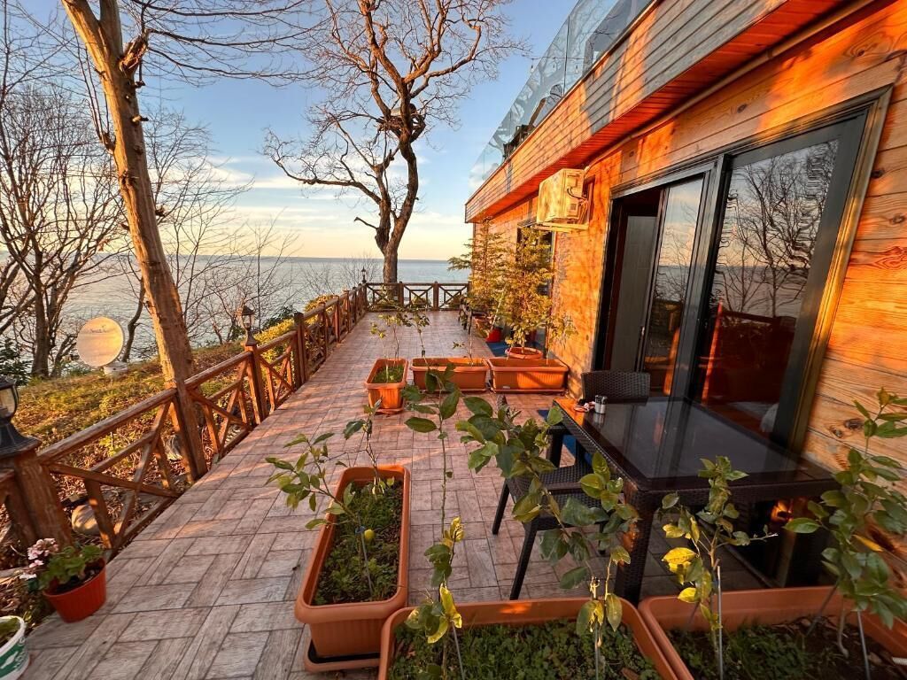 A wooden deck with potted plants, a table, and chairs.