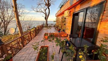 A wooden deck with potted plants, a table, and chairs.