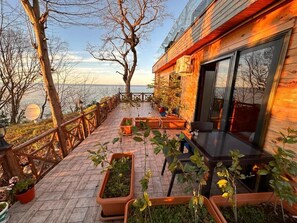 A wooden deck with potted plants, a table, and chairs. - Falez Cafe Restorant Pansiyon - Arhavi (Arhavi)