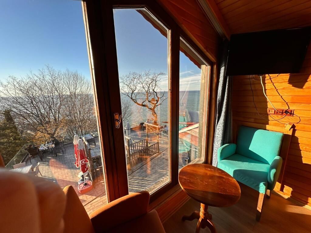 Ein Zimmer mit einem großen Fenster, einem türkisfarbenen Sofa und einem Holztisch.