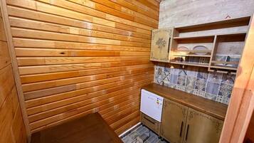Una cocina compacta con paredes de madera, salpicadero de azulejos y un refrigerador pequeño.