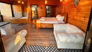 En stuga med träpanel på insidan, inredd med en säng, en soffa, ett badkar och ett golv med ett mönster.