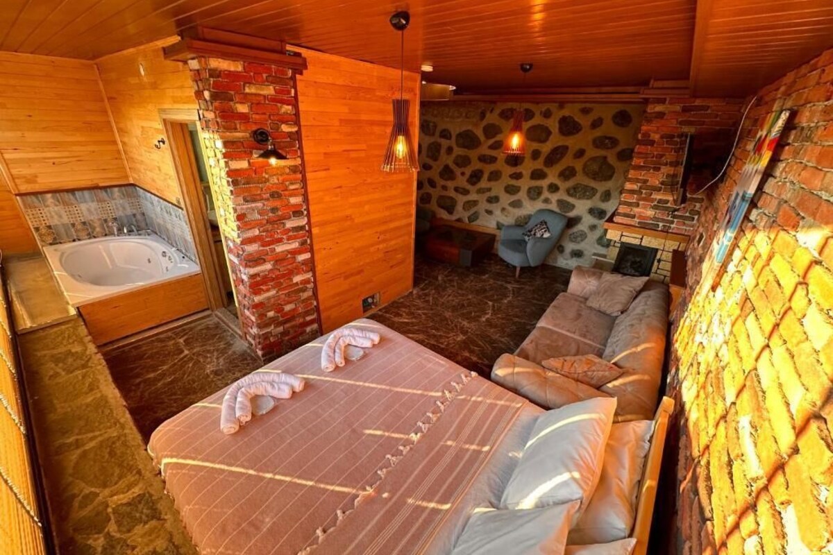 Un interior de madera con una cama, una bañera y una pared de piedra.