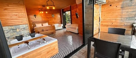 A wooden cabin interior with a bathroom, a dining area, and a seating space.