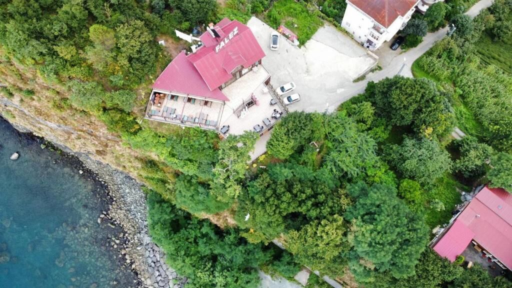Vista aérea de una propiedad con un edificio de techo rojo, un camino pavimentado y un exuberante paisaje verde circundante.