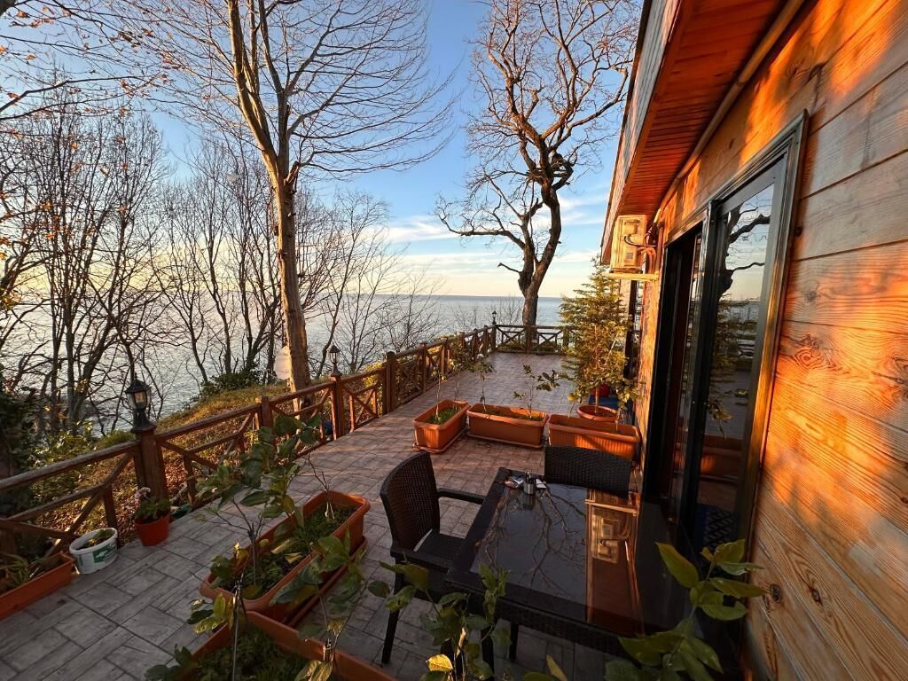 A wooden deck with outdoor seating, overlooking a body of water.