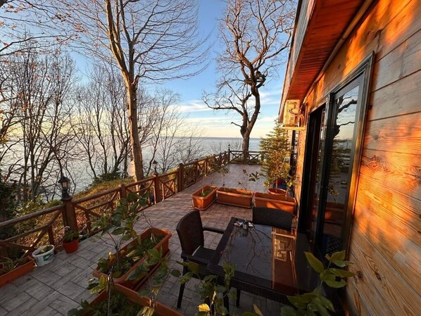 A wooden deck with outdoor seating, overlooking a body of water.