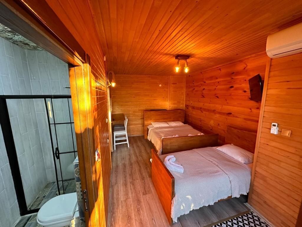 Eine Holzhütte mit zwei Betten, einer Dusche und einer weißen Toilette.