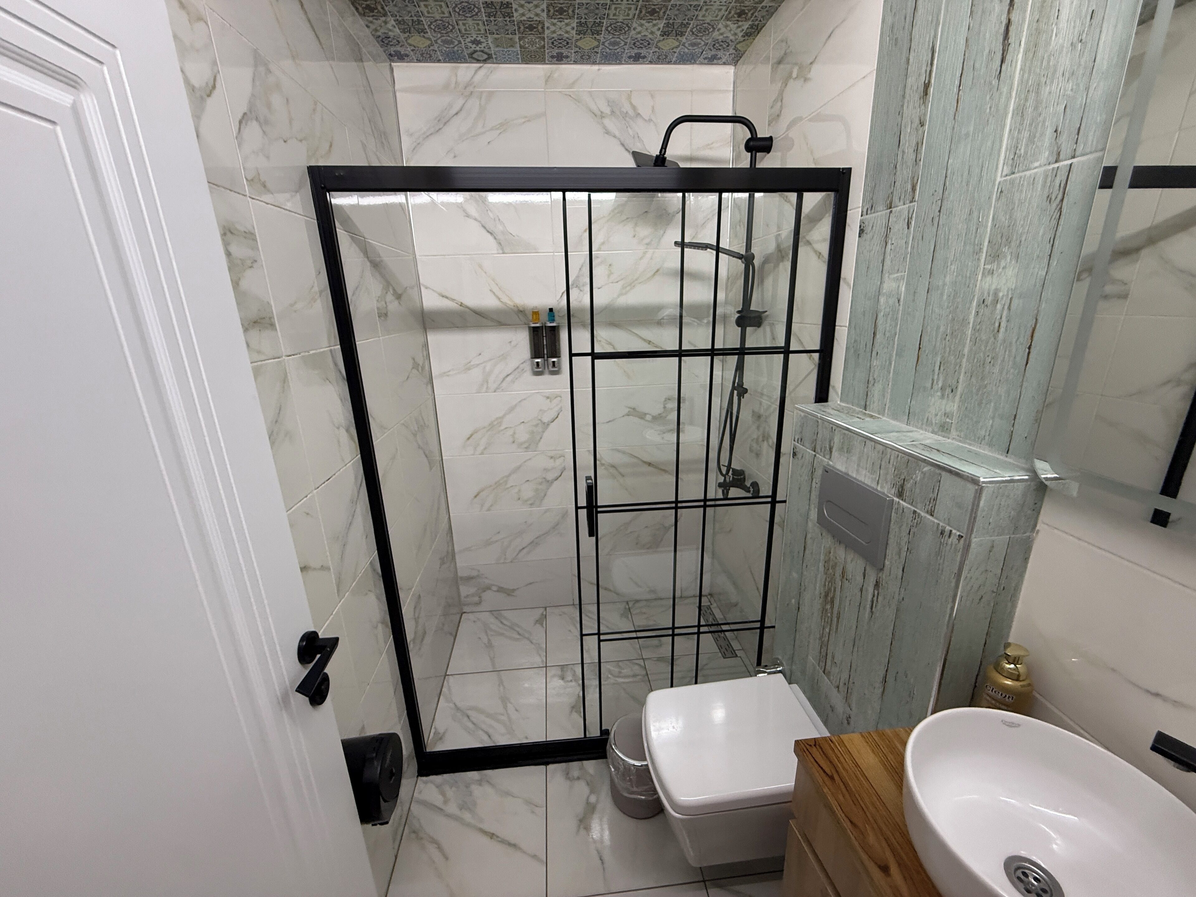 A bathroom with a glass-enclosed shower, a white toilet, and a sink with a wooden countertop.