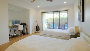 A bedroom with two beds, a desk with a computer, a guitar, and a balcony with chairs. - Unwind Poolside, Walk Dtwn! Palm Springs Retreat (Palm Springs)