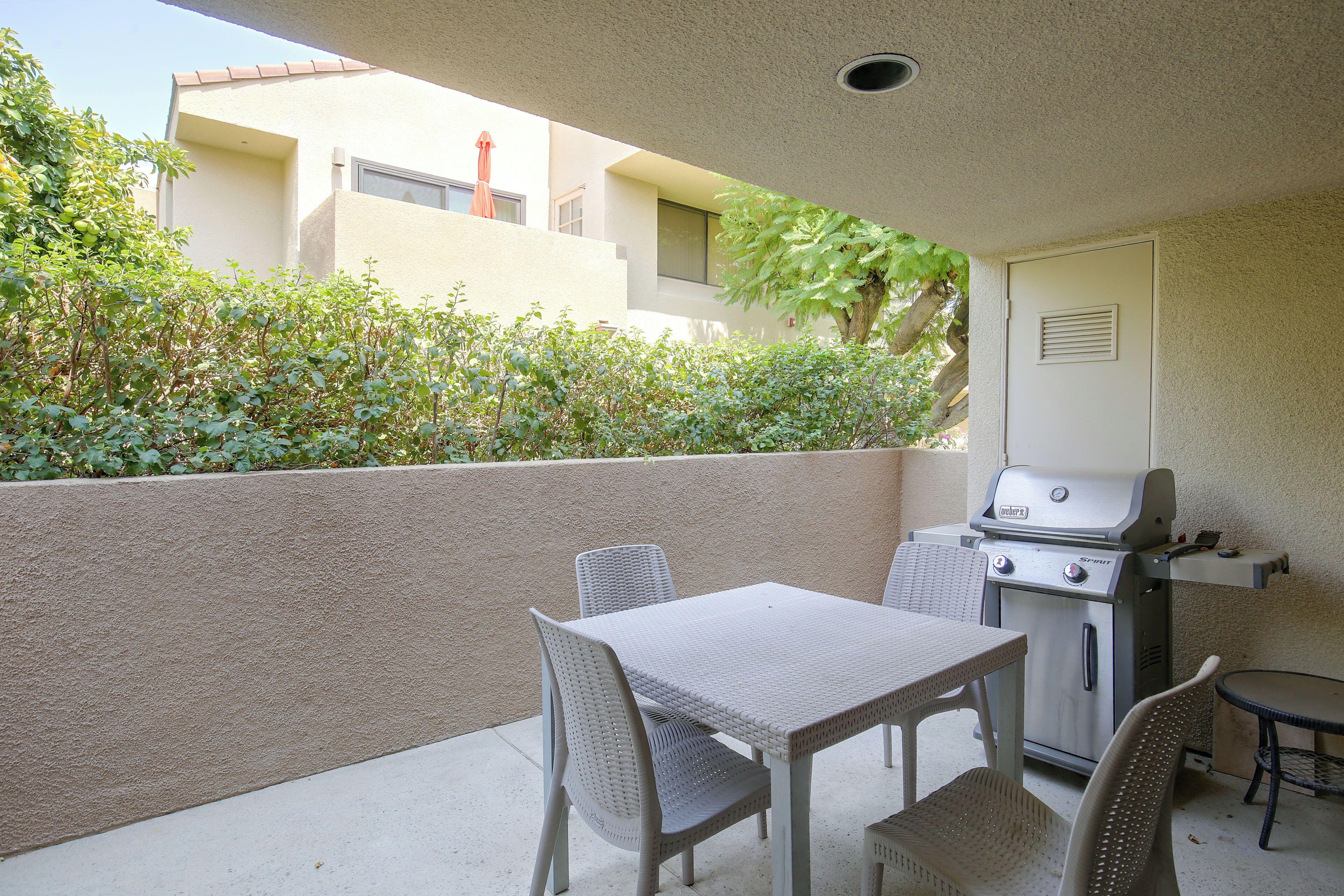 Ulkoterassi, jossa on grilli, kaksi rottingista tuolia ja pieni pöytä.