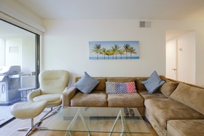 A living room with a glass coffee table, a beige sofa, and a painting of palm trees. - Unwind Poolside, Walk Dtwn! Palm Springs Retreat (Palm Springs)