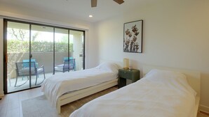 A bedroom with two beds, a ceiling fan, a window with a view of greenery, and a framed picture on the wall. - Unwind Poolside, Walk Dtwn! Palm Springs Retreat (Palm Springs)