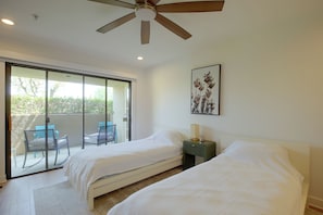 A bedroom with two beds, a ceiling fan, a window with a view of greenery, and a framed picture on the wall. - Unwind Poolside, Walk Dtwn! Palm Springs Retreat (Palm Springs)