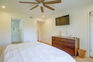A bedroom with a bed, a wooden dresser, a television mounted on the wall, and a glass shower enclosure. - Unwind Poolside, Walk Dtwn! Palm Springs Retreat (Palm Springs)