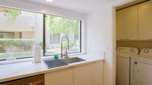 A kitchen with a window, a sink, a faucet, and a washing machine. - Unwind Poolside, Walk Dtwn! Palm Springs Retreat (Palm Springs)