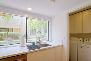 A kitchen with a window, a sink, a faucet, and a washing machine. - Unwind Poolside, Walk Dtwn! Palm Springs Retreat (Palm Springs)