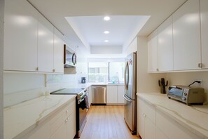 A modern kitchen with white cabinetry, a built-in oven, and a refrigerator. - Unwind Poolside, Walk Dtwn! Palm Springs Retreat (Palm Springs)