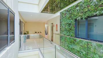 Ein modernes Interieur mit Glastrennwand, Treppe und einer mit Grünpflanzen bewachsenen Wand.