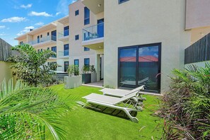 Ein modernes Mehrfamilienhaus mit Balkonen, einer Terrassenlounge und einem gepflegten Garten.