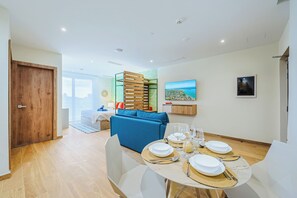 Un salon moderne comprenant un coin repas, un canapé, un téléviseur et un tableau accroché au mur.