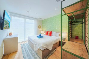 A modern hotel room with a large bed, a desk, a view of the city, and a green patterned wall. - Bonsai Studio-Hikari 209 (Noord)