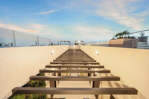 A modern staircase leading to a beach area with a clear sky. - Bonsai Studio-Airy 202 (Noord)