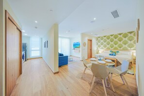 A modern interior with a dining area, a living space with a blue sofa, and a kitchen area. - Bonsai Studio-Airy 202 (Noord)