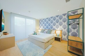 Ein modernes Schlafzimmer mit einem großen Bett, Nachttischen, einem Kleiderschrank und Blick ins Freie.
