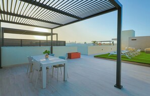 Eine Dachterrasse mit Tisch und Stühlen, einem Blumentopf und einem roten Pflanzgefäß.