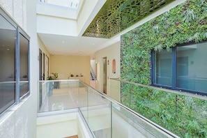 A modern interior with a glass railing, a staircase, and a wall covered in greenery. - Bonsai 1BR Suite-Blue Glow 105 (Noord)