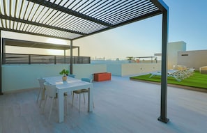 Eine Dachterrasse mit Tisch und Stühlen, einem Blumentopf und einem roten Pflanzgefäß.