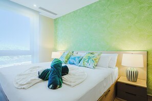 Una habitación de hotel con una cama grande, una mesita de noche con lámpara y una ventana con vistas.
