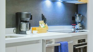 Ett modernt kök med en kaffebryggare, ett knivställ och en mixer på bänkskivan.