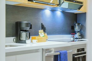 A modern kitchen with a coffee maker, knife block, and a blender on the counter. - Bonsai 1BR Suite-Breezy Palm 208 (Noord)