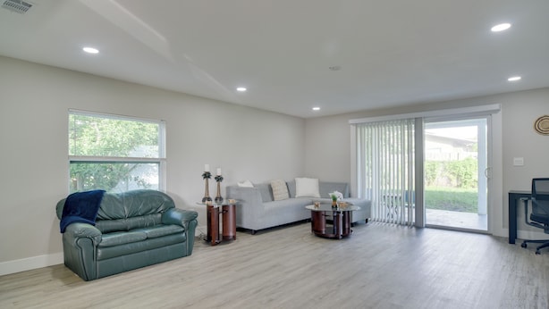 A spacious living room with a grey sofa, a green leather couch, and a round coffee table. - Suntan, Shop & Explore! Seminole Escape (Seminole)