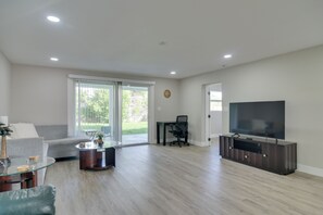 Una sala de estar moderna con un sofá, una mesa de centro, televisor y un ventanal corredero que da a un patio.