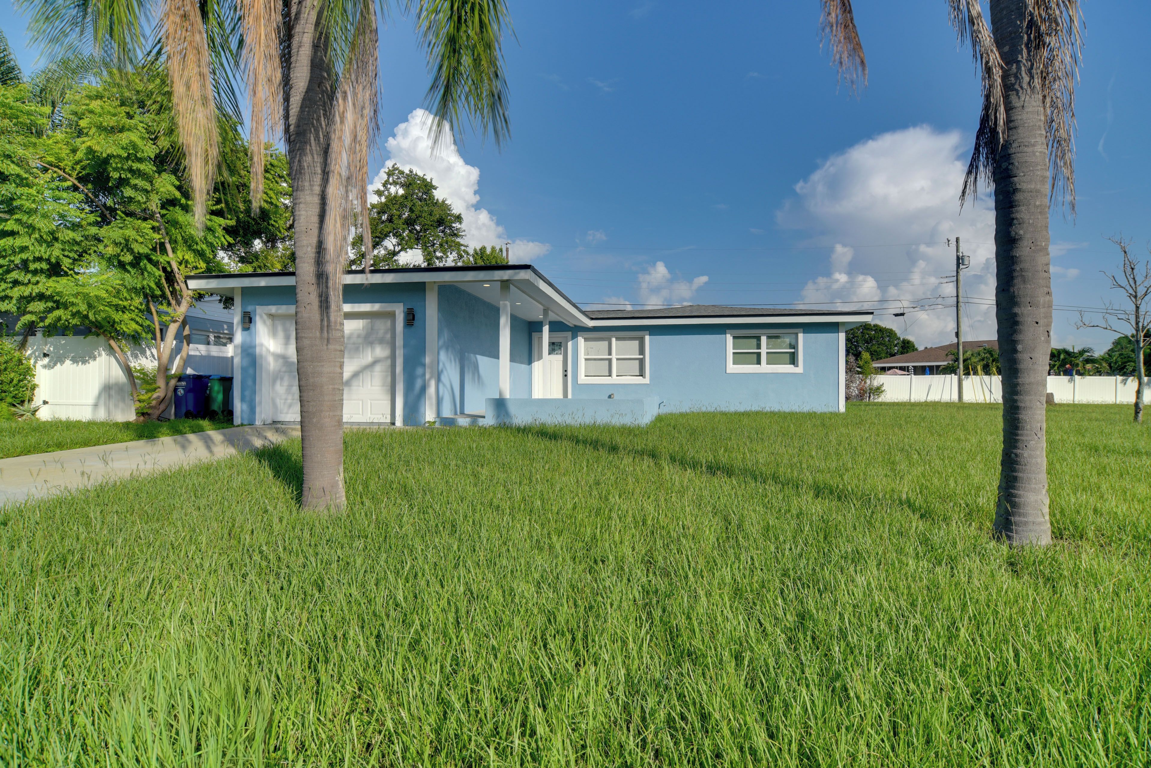 A single-story house with a blue exterior, a front porch, and a grassy yard.