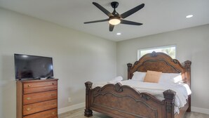 A bedroom with a wooden bed, a dresser, a television, and a ceiling fan. - Suntan, Shop & Explore! Seminole Escape (Seminole)