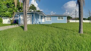 A single-story house with a blue exterior, a front porch, and a grassy yard. - Suntan, Shop & Explore! Seminole Escape (Seminole)