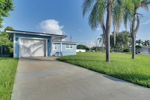 A single-story house with a garage, surrounded by grass and palm trees. - Suntan, Shop & Explore! Seminole Escape (Seminole)